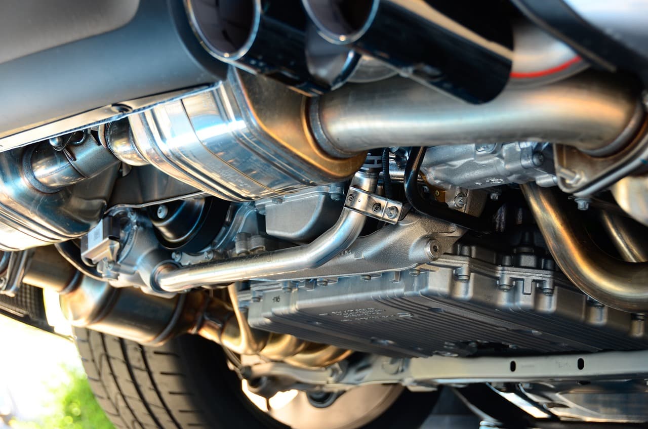 The underside of a car on a lift: exhaust pipes, catalytic converter and sump