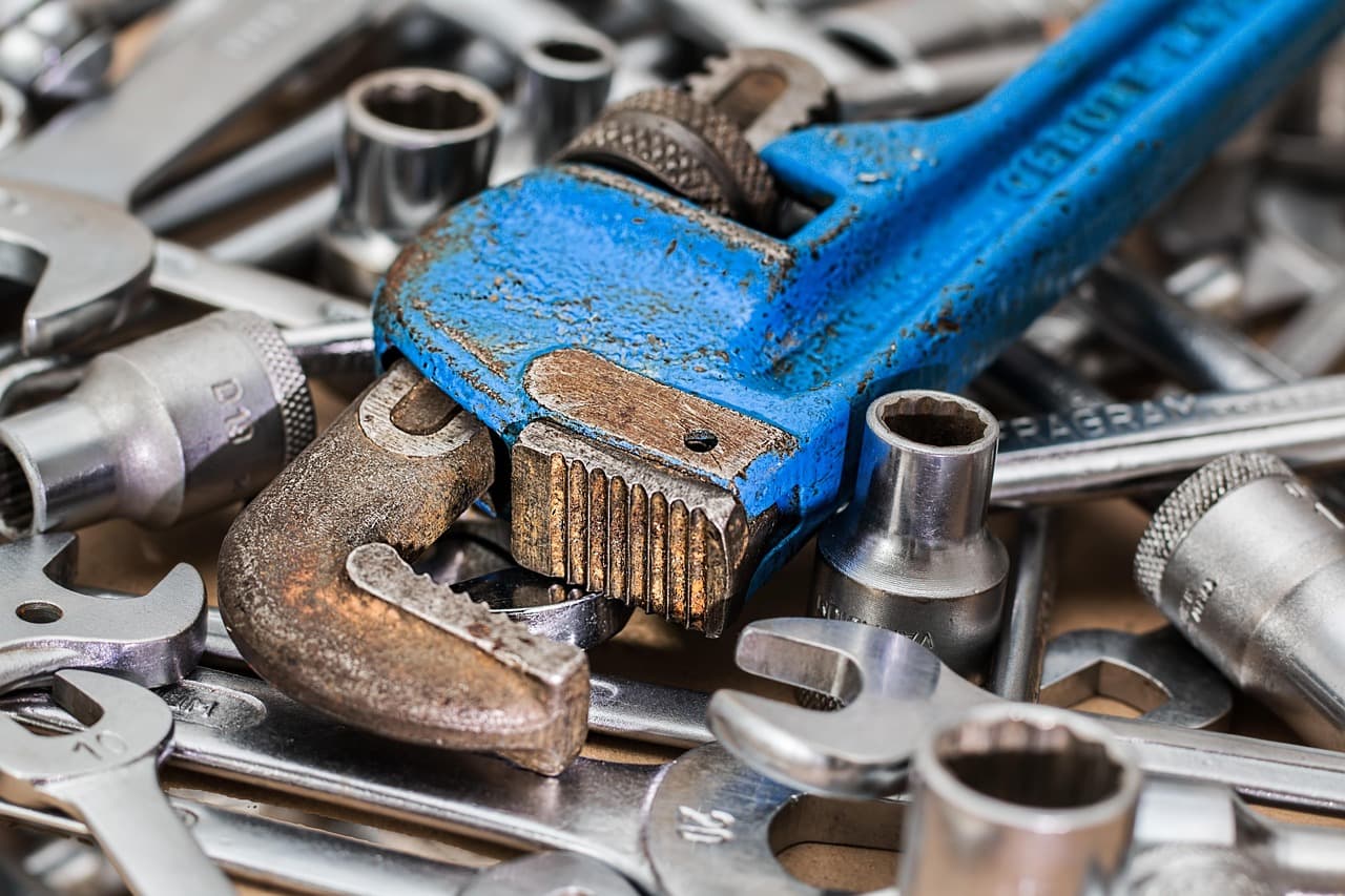 Spanners, sockets and an adjustable wrench in a pile on the bench